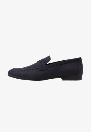 Mocassin bleu foncé pour homme, à enfiler, avec un petit talon, une couture style mocassin et une bride sur le dessus.