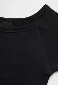 Fekete pamut póló kerek nyakkivágással, rövid ujjú és sima tapintású. Látható varrásokat és méretcímkét tartalmaz.