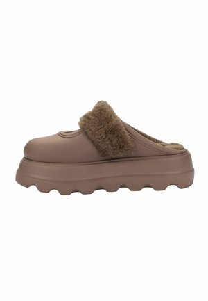 Zueco marrón tipo slip-on con suela gruesa y texturizada y forro de piel suave alrededor del talón y en el interior para mayor calidez y comodidad.