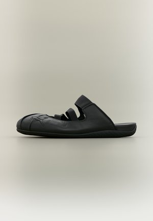 Chaussure noire à enfiler avec bout fermé, trois brides élastiques sur le dessus, semelle plate et logo Puma embossé sur le côté.