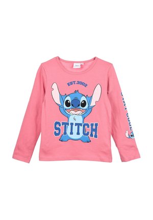 Chemise rose à manches longues avec grand personnage de dessin animé bleu Stitch, texte "EST. 2002" en haut et "STITCH" en bas sur le devant, et un Stitch plus petit sur la manche.