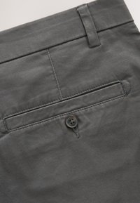 Pantalon en tissu gris foncé avec poche arrière passepoilée à bouton et passants de ceinture à la taille.