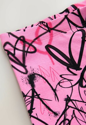 Rosa Stoff mit abstrakten, graffitiartigen Mustern in Schwarz und Rot. Die Textur wirkt glatt mit sichtbaren Nähten entlang des Randes.