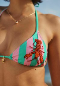 Bikini de triángulo con rayas rosas y verdes, con un diseño detallado de una langosta con cuentas naranjas en la copa izquierda. Tirantes ajustables para mejorar el ajuste.