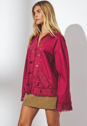 Langemouwen bordeaux rode shirt met ingewikkelde kantdetails langs de voorkant en manchetten, met een gekraagde hals en een losse pasvorm.