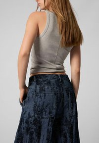 Helehallid ilma varrukateta topp ja tumehallid tekstuuriga laiad püksid tagakottidega, millel on pleekinud muster.