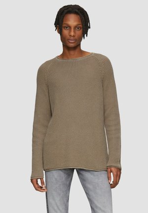 Beiger Strickpullover mit lockerer Passform, rundem Halsausschnitt und langen Ärmeln. Besitzt ein strukturiertes Gewebe und einen gerippten Saum. Kombiniert mit hellen Jeans.