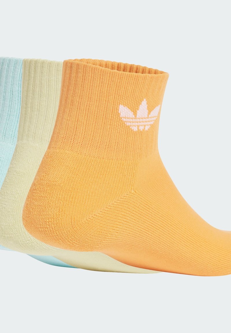 Trzy pary krótkich skarpetek: pomarańczowe, jasnobrązowe i jasnoniebieskie. Wykonane z gładkiego dzianinowego materiału, z białym logo na pomarańczowej parze.