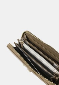 Cartera marrón con cremallera y múltiples compartimentos, incluyendo ranuras para tarjetas de crédito y una ventana transparente para identificación, con herrajes en tono dorado y acabado texturizado.
