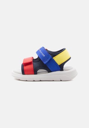 Children’s open-toe sandal with red, blue, and yellow adjustable straps and white cushioned sole.