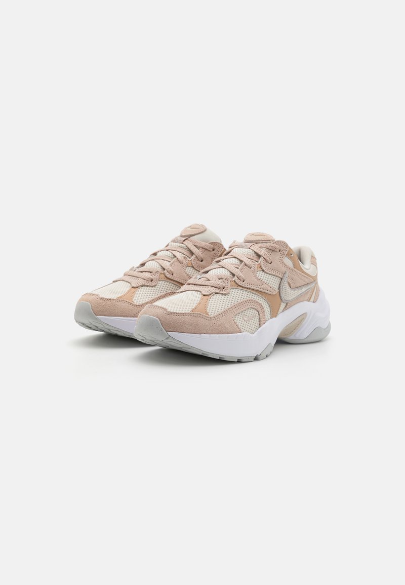 Des chaussures de sport avec une combinaison de maille rose clair et de suède beige. Le design comprend des lacets, une semelle rembourrée et un logo discret.