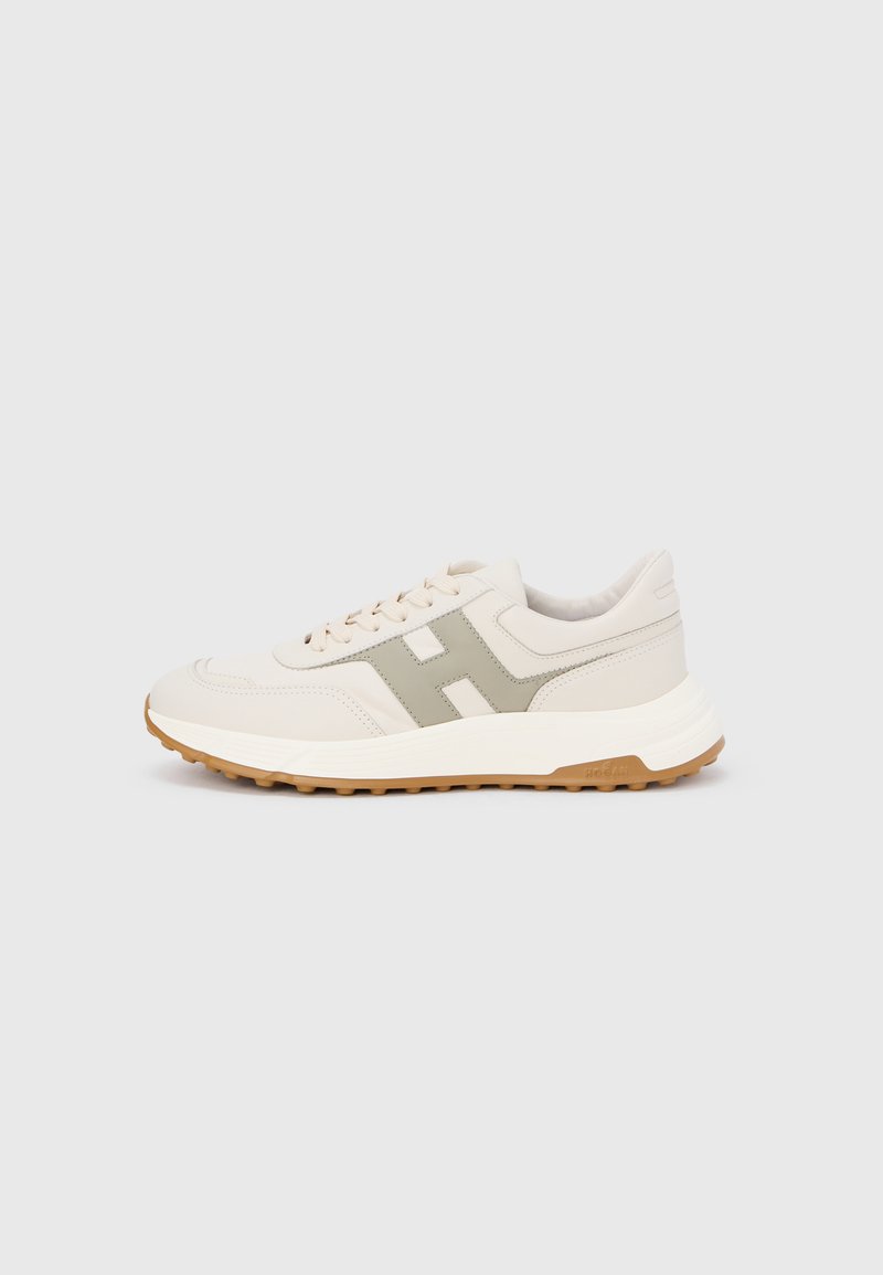 Baskets beige clair avec une tige en cuir lisse, des accents verts, une fermeture à lacets et une semelle extérieure en caoutchouc gomme texturée.