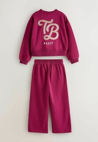 Vaaleanpunainen huppari ja siihen sopivat housut, joissa on suuri kimaltava "TB"-logo ja "BAKER"-teksti, ribbed hihansuut ja joustava vyötärö.