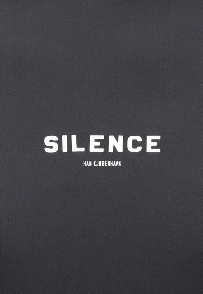 Čierna tkanina s textúrovaným povrchom, na ktorej je výrazný biely nápis "SILENCE" a pod ním v menšom písmene "HAN KJØBENHAVN".