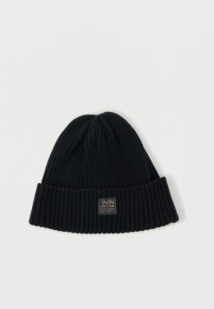 Beanie nero lavorato a maglia con texture a costine, risvolto, e una piccola etichetta rettangolare con un logo. Tessuto morbido e caldo.