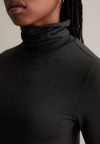 Langärmliges schwarzes Rollkragenoberteil mit einem dezenten strukturierten, schimmernden Finish. Verfügt über einen hohen Ausschnitt und eine figurbetonte Silhouette.