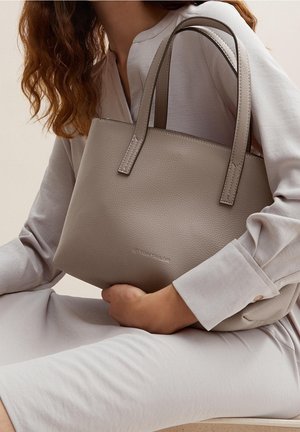 Grå tekstureret håndtaske med to korte håndtag, der har et simpelt design. Tasken står mod en lys neutral baggrund.