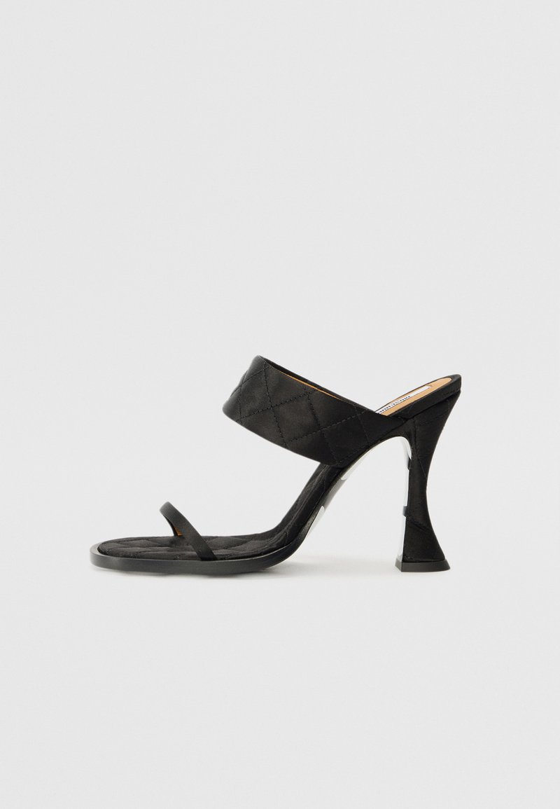 Schwarze High-Heelsandalen mit einem gepolsterten Oberriemen und einem dünnen Knöchelriemen. Bietet eine einzigartige skulptierte Fersenform. Glatte Textur.