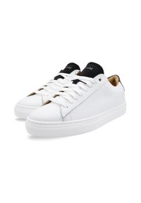 White leather sneakers with a textured surface, black accents on the tongue, and a rubber sole. Features round laces and minimalistic design.