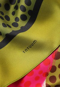 Écharpe en soie avec un fond vert, des pois noirs et des accents roses vifs, imprimée avec "TNTUUM". Texture douce et bords roulés.