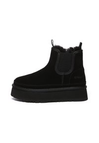 Black suede ankle boot with elastic side panels, plush interior, and thick rubber sole. Features a pull tab and subtle branding. Simplistic design.