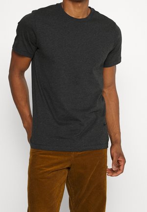 T-shirt en coton gris foncé avec un col rond et des manches courtes, présenté avec un pantalon en velours côtelé couleur fauve à texture verticale.