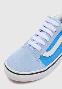 Zapatillas de deportiva de ante y lona azul con cordones blancos, una franja lateral blanca y suela de goma negra con detalles texturizados.