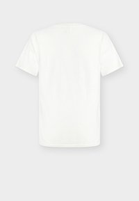 Απλό λευκό μπλουζάκι με κοντά μανίκια, εμφανιζόμενο από πίσω σε ουδέτερο γκρι φόντο, χωρίς ορατά λογότυπα ή σχέδια.