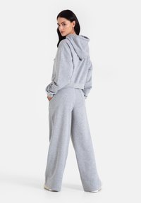 Szara bluza z kapturem o krótkim kroju, w połączeniu z luźnymi szarymi spodniami dresowymi. Wykonana z miękkiego materiału, posiada kieszenie i luźny fason.