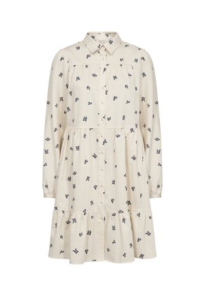 Button-up obleka iz kremaste tkanine s teksturiranim vzorcem; vsebuje mornarsko modre cvetlične dodatke, dolge rokave in zasnovo v več plasteh.