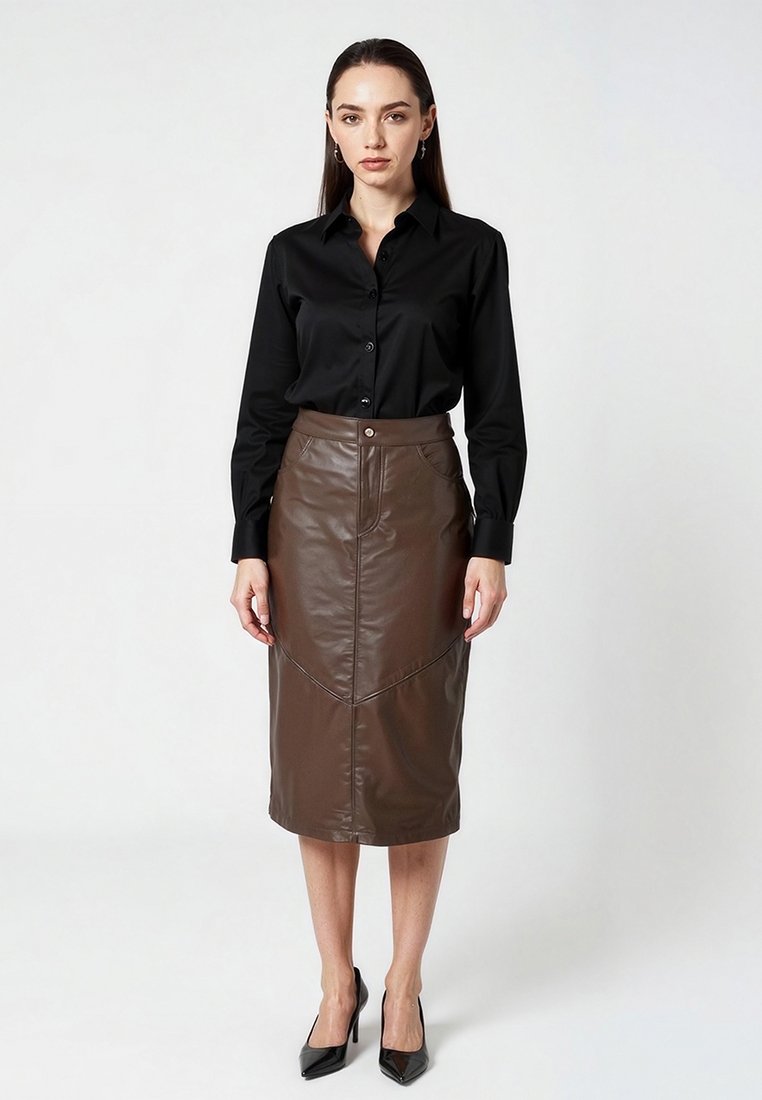 Jupe crayon en fausse cuir marron avec des détails de couture en biais, taille haute et fermeture à boutons à l'avant, associée à une chemise noire à boutons et des talons.
