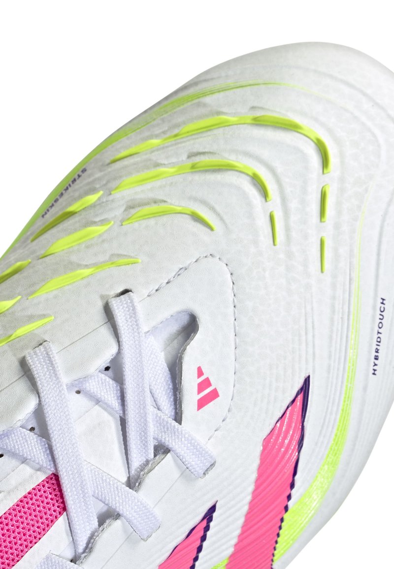 Scarpa sportiva bianca con materiale testurizzato, dettagli in neon giallo, strisce rosa e lacci bianchi; presenta un design ibrido con modelli distintivi.
