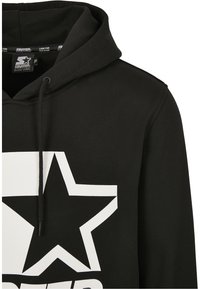 Sweat à capuche noir avec grand graphisme étoile blanche et texte noir en dessous, doté d'une capuche réglable par cordon et d'une étiquette de la marque Starter à l'intérieur du col.