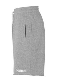 Grijze katoenen shorts met een elastische tailleband, zijzakken en een wit "Kempa" logo aan de onderkant aan de linkerkant. Glad textuur, knielange design.