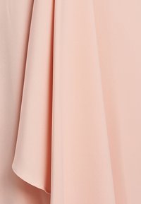 Light pink fabric drapes with a smooth, slightly glossy texture; features gentle folds and a soft finish, showcasing its lightweight design.