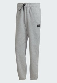 Graue Jogginghose mit elastischem Bund und verstellbarem Kordelzug. Mit Seitentaschen und einem kleinen schwarzen Logopatch am Oberschenkel.