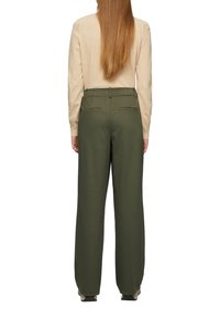 Groene wijde broek van zacht materiaal, met achterzakken en een middelhoge tailleband, gestyled met een crèmekleurige trui.