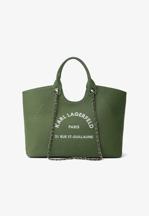 Grøn canvas mulepose med to håndtag, sølvkæde og hvid tekst "KARL LAGERFELD PARIS 21 RUE ST-GUILLAUME" foran.