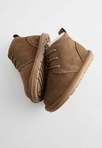 Braune Wildleder-Stiefeletten mit Schnürdesign, weicher Innenausstattung und strukturiertem Gummisohl. Runde Zehenform und eine Zuglasche an der Rückseite.