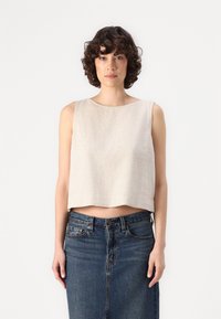 Bež cropped top s okruglim izrezom, napravljen od laganog materijala. Uparen s plavom traper suknjom klasičnog kroja.
