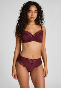 Bordeaux lingerie-set met een beha met kantafwerking en een stippenpatroon, gecombineerd met bijpassende slipjes die kantaccenten bij de taille hebben.