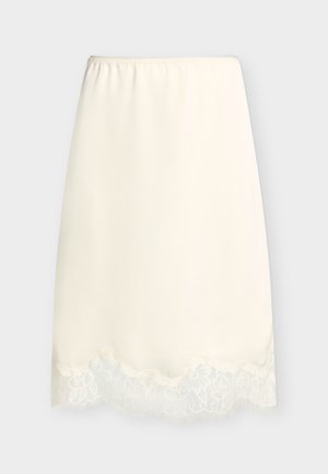 Fustă half slip crem cu talie elastică și margine din dantelă de-a lungul tivului, expusă pe un fundal simplu și deschis la culoare.