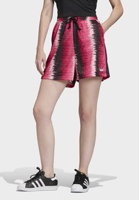 Růžové a černé sportovní šortky se vzorem, s elastickým pasem a šňůrkou, mají boční kapsy a malé logo na lemu.