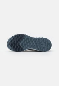 Suela de zapato con agarre texturizado que presenta un patrón hexagonal en gris oscuro, con un borde liso que se estrecha hacia una base de color gris más claro.