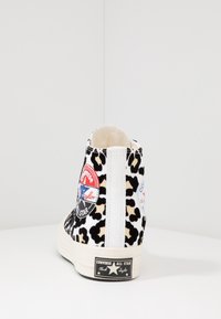 Zapatillas Converse de caña alta con estampado de leopardo y acentos en negro, suela de goma blanca y parches de logo en rojo, blanco y azul.
