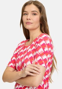 Korte ærmer skjorte med et geometrisk mønster i pink, rød og hvid, rund halsudskæring, blødt stof og afslappet pasform.