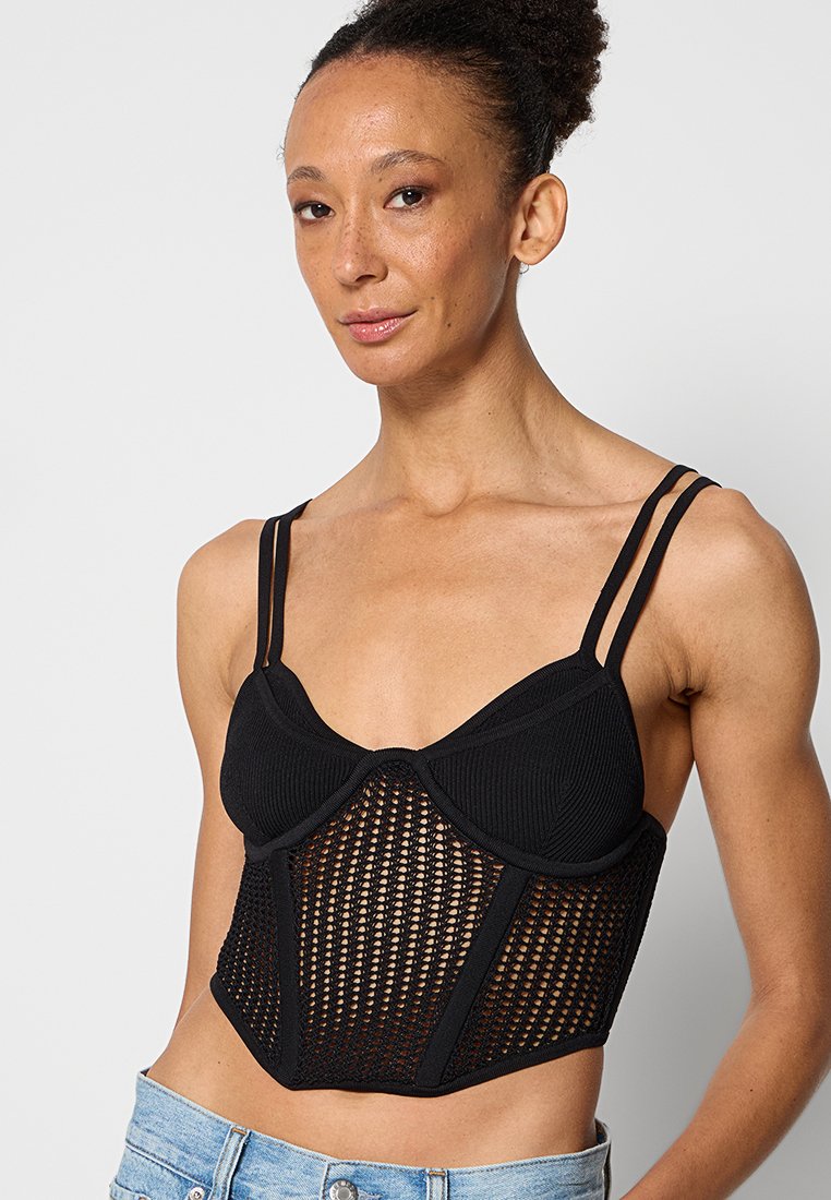 Schwarzes Cropped Top mit ribbeligem oberen Bereich und unterem Teil aus Netzstoff. Es hat dünne Träger und eine strukturierte Silhouette mit geometrischen Mustern.