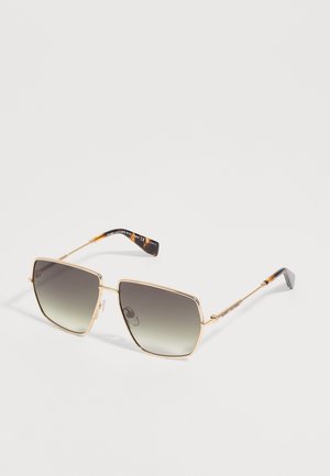 Lunettes de soleil carrées à monture dorée avec verres dégradés foncés et branches fines ornées d'embouts en écaille de tortue sur fond blanc.
