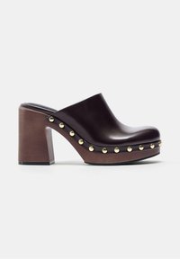 Sabot en cuir marron foncé avec bordure cloutée, semelle plateforme en bois et talon bloc épais, style slip-on.