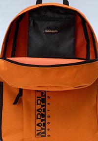 Zaino in tela arancione con un ampio scomparto principale e una tasca interna nera con zip. Presenta una fodera in rete e una stampa del logo.